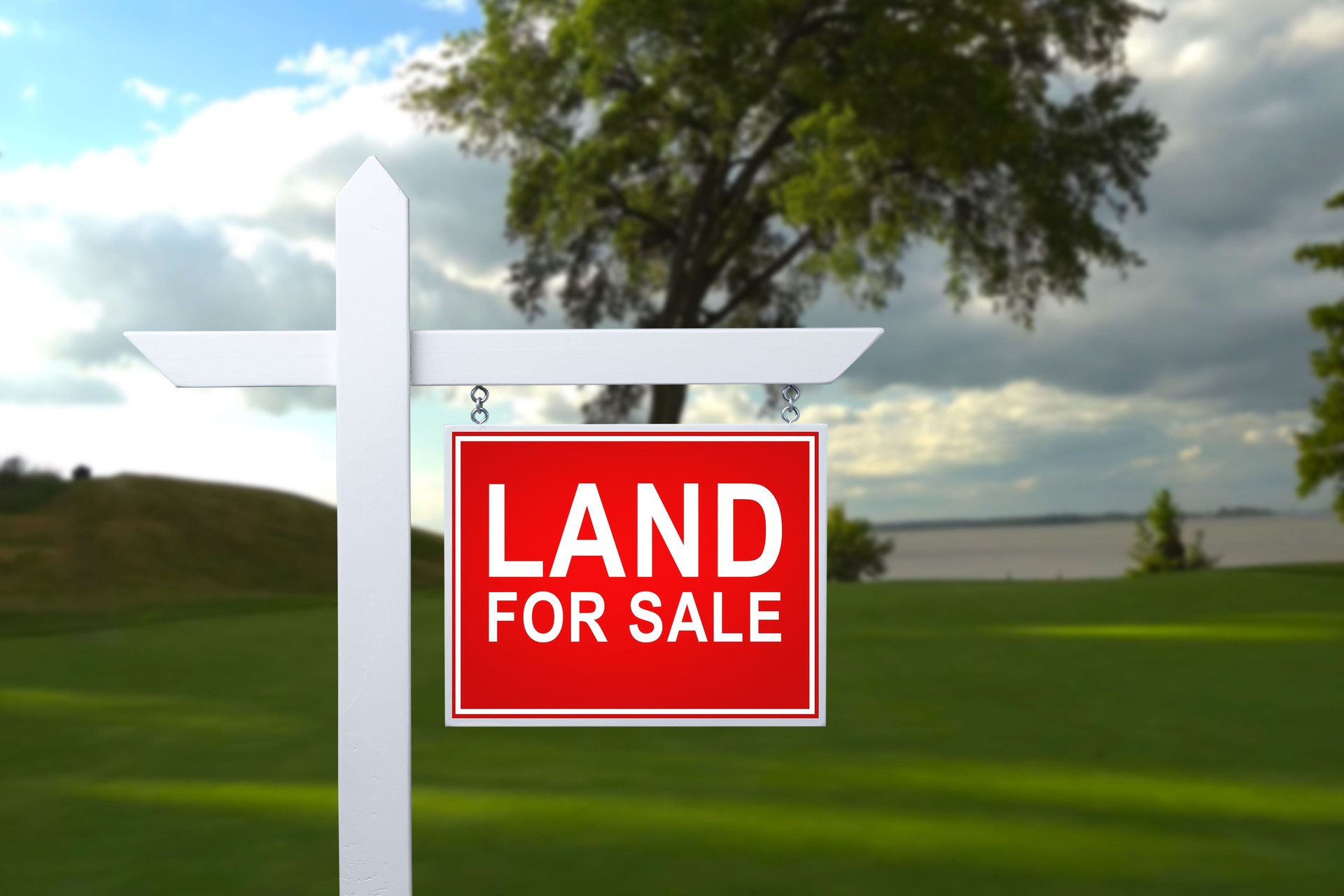 LAND FOR SALE SIGN on empty meadow - Real estate conceptual image.